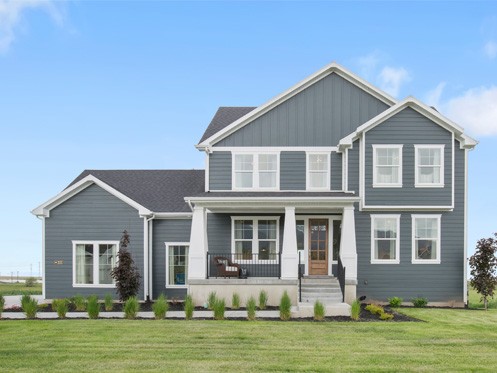 A two-story modern house with gray siding, white trim, and a covered front porch. The yard is landscaped with grass, shrubs, and small trees. The sky is clear with a few clouds. | High 5 Plumbing, Heating & Cooling
