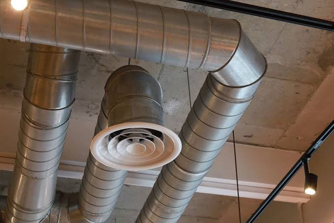 Metal HVAC ductwork and ceiling air vent in an exposed indoor ceiling.